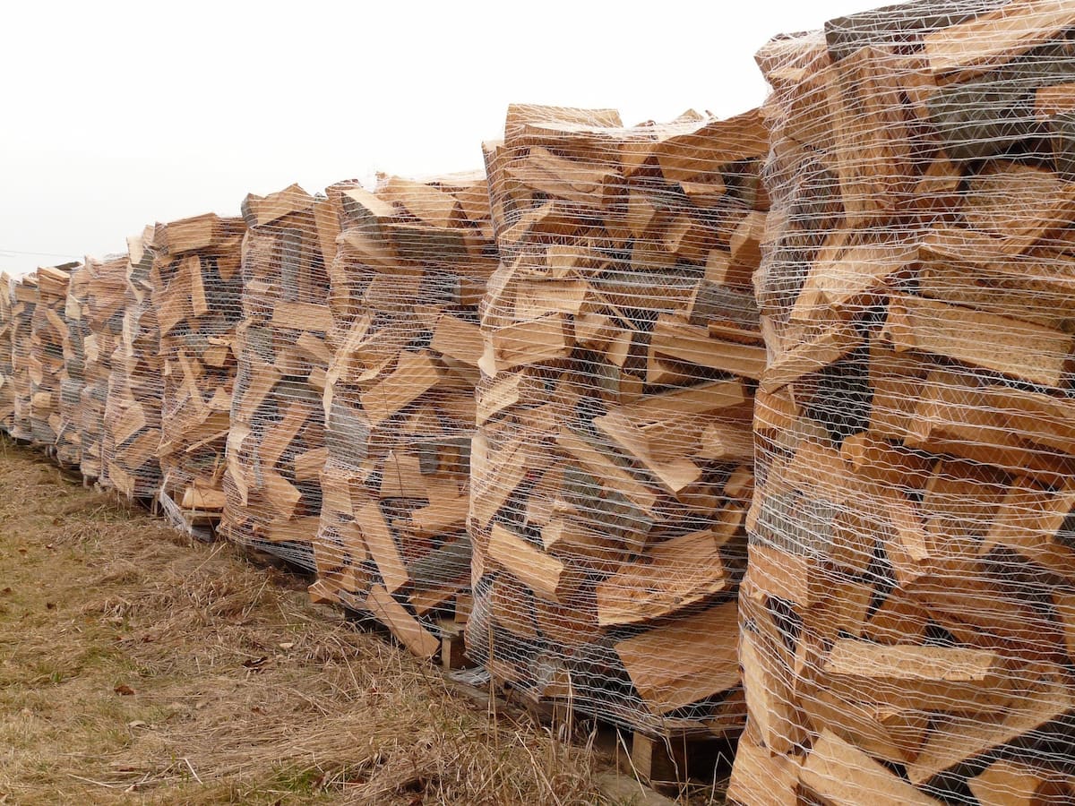 Stacked retail firewood bundles wrapped in plastic netting, kiln-dried for indoor and campfire use